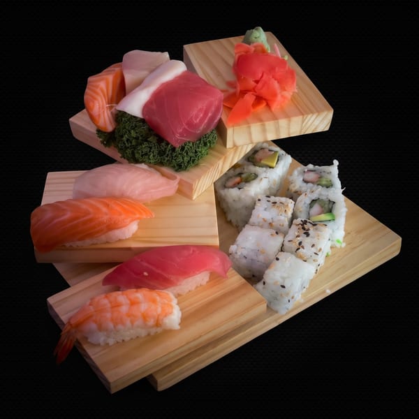 Assorted sushi and sashimi on wooden serving boards, including salmon, tuna, and California rolls.