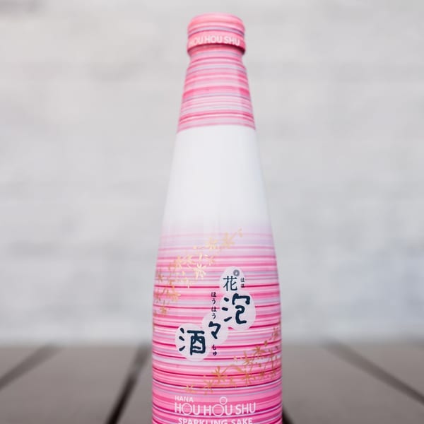 A bottle of Hana Hou Hou Shu Sparkling Sake, with a pink and white label featuring cherry blossoms.